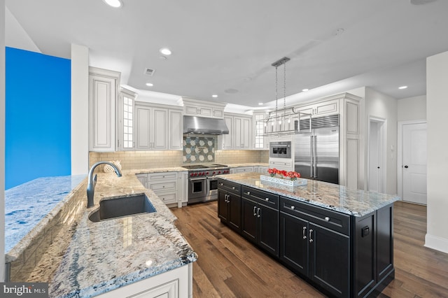 kitchen featuring dark hardwood / wood-style flooring, hanging light fixtures, sink, high quality appliances, and a kitchen island