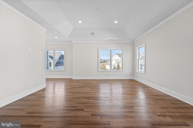 unfurnished living room featuring ornamental molding, a tray ceiling, a healthy amount of sunlight, and dark hardwood / wood-style floors