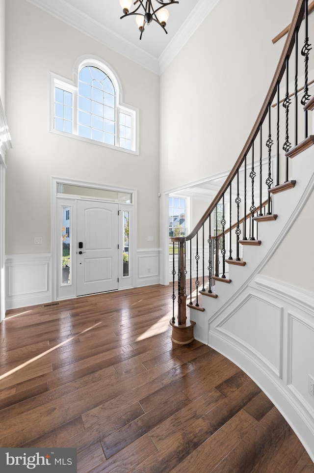 foyer with hardwood / wood-style floors, a wealth of natural light, a high ceiling, and crown molding