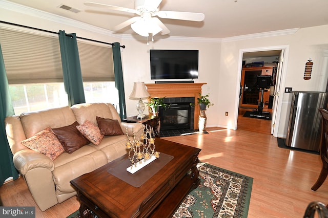 living room with crown molding, light hardwood / wood-style flooring, a fireplace, and ceiling fan