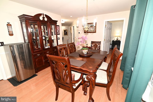 dining room with light hardwood / wood-style floors and a notable chandelier