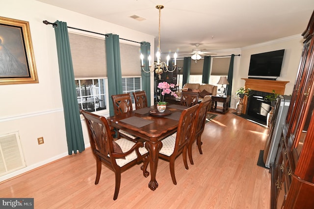 dining space with light hardwood / wood-style floors, ornamental molding, and ceiling fan with notable chandelier