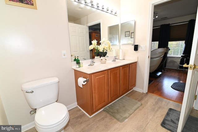 bathroom with toilet, hardwood / wood-style flooring, and vanity