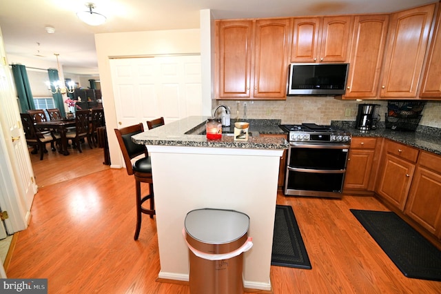 kitchen featuring light hardwood / wood-style flooring, stainless steel appliances, sink, a breakfast bar, and tasteful backsplash