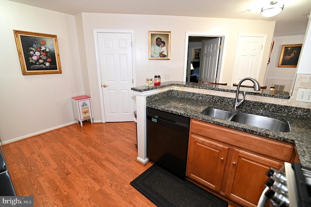 kitchen with sink, wood-type flooring, dishwasher, and dark stone counters