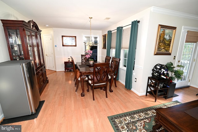 dining room with crown molding, light hardwood / wood-style flooring, and a chandelier