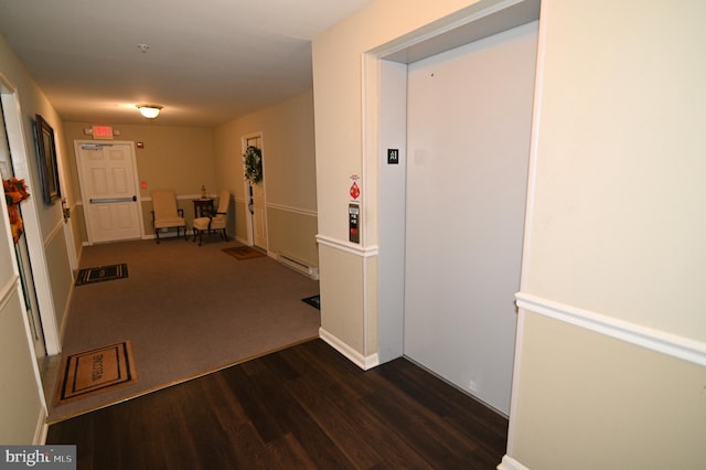 corridor featuring a baseboard heating unit and dark hardwood / wood-style flooring