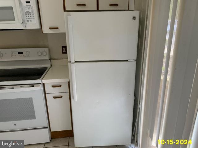 kitchen with white cabinetry, white appliances, and light tile patterned floors