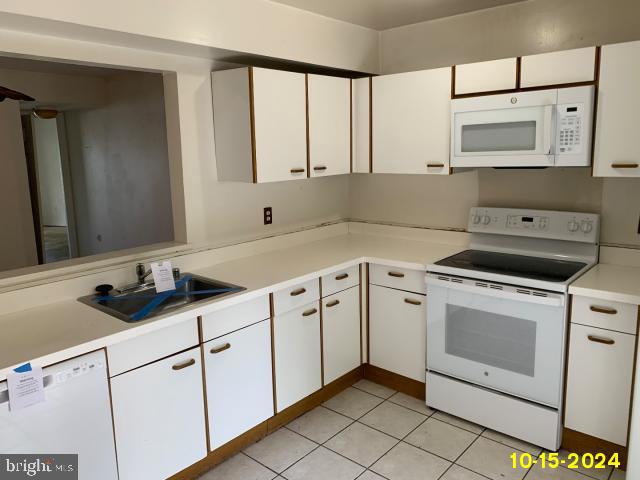 kitchen featuring white cabinetry, sink, white appliances, and light tile patterned flooring