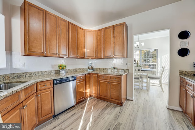 kitchen with decorative backsplash, light stone countertops, a chandelier, light hardwood / wood-style flooring, and dishwasher