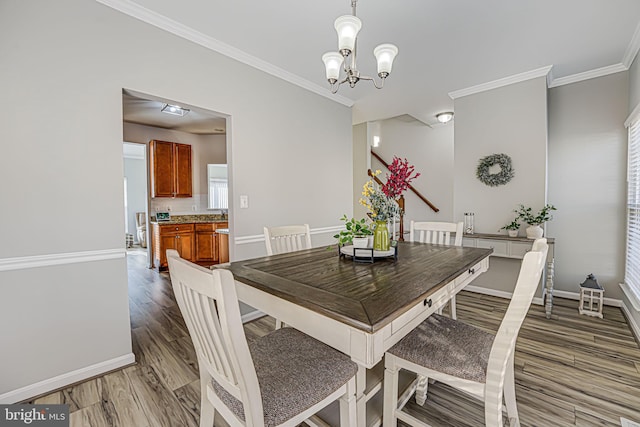 dining area with an inviting chandelier, crown molding, and wood-type flooring