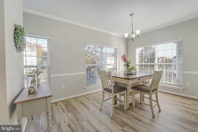 dining area with crown molding, a notable chandelier, and light hardwood / wood-style flooring