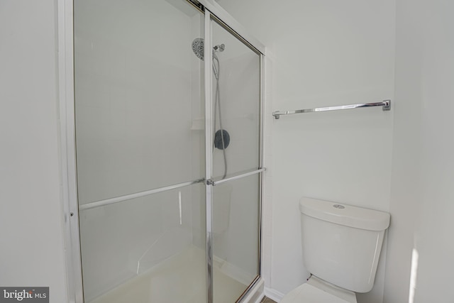 bathroom with toilet and a shower with door