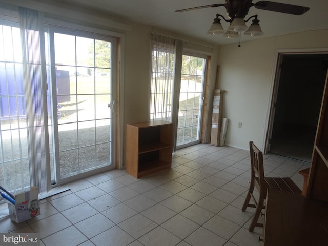 doorway with ceiling fan and light tile patterned floors