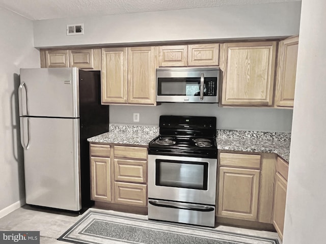 kitchen with light stone countertops, appliances with stainless steel finishes, and light brown cabinets