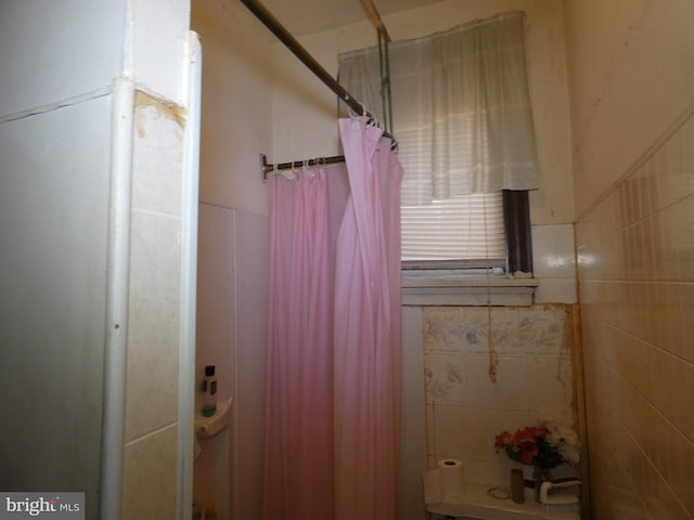 bathroom with tile walls and curtained shower