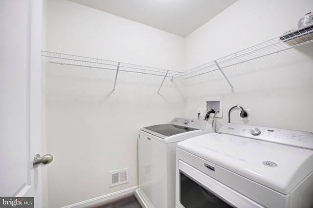 laundry room with washer and dryer and hardwood / wood-style flooring