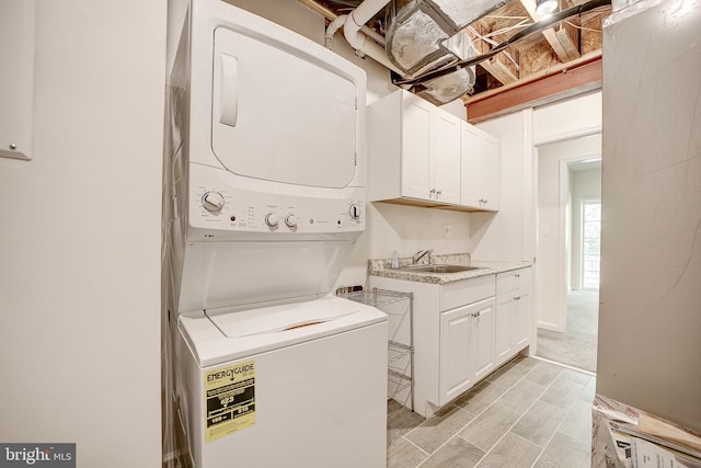 washroom featuring sink, stacked washer / drying machine, and cabinets