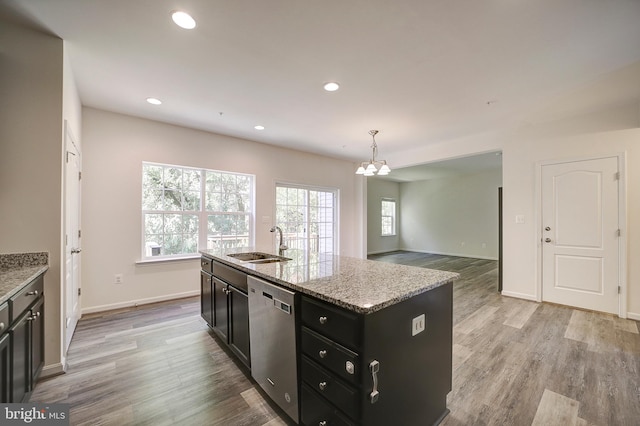 kitchen with sink, light wood-type flooring, decorative light fixtures, stainless steel dishwasher, and a center island with sink