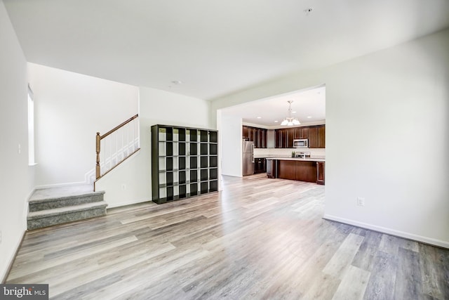 unfurnished living room with a chandelier and light wood-type flooring