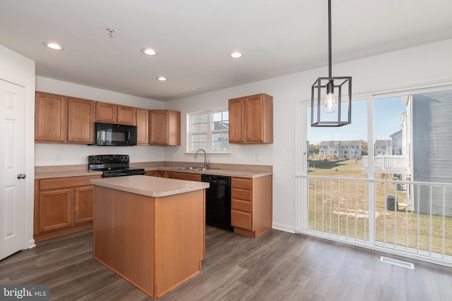 kitchen featuring black appliances, sink, a kitchen island, dark hardwood / wood-style flooring, and decorative light fixtures