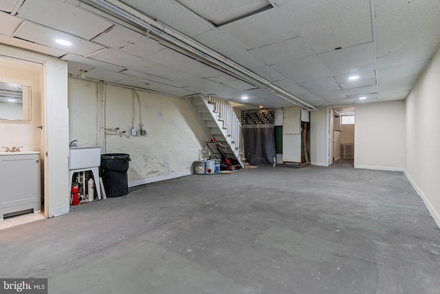 basement with a paneled ceiling and sink