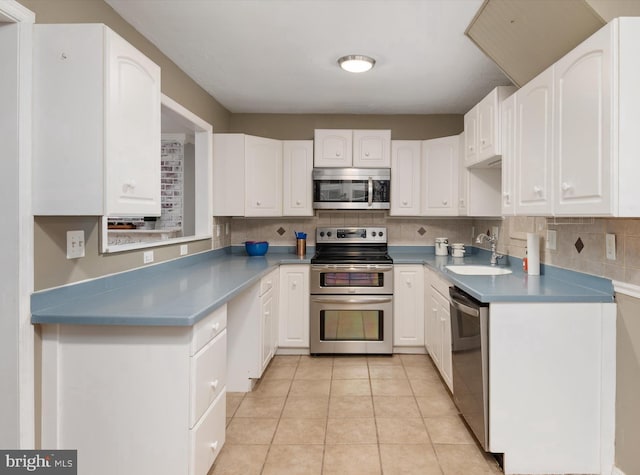 kitchen featuring white cabinets, stainless steel appliances, light tile patterned flooring, and sink