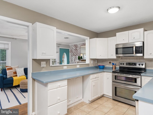 kitchen with tasteful backsplash, white cabinetry, light tile patterned flooring, and appliances with stainless steel finishes