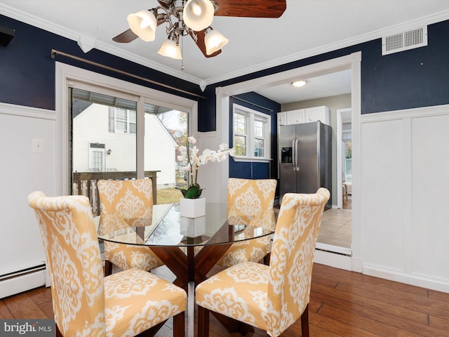 dining area featuring a baseboard heating unit, hardwood / wood-style flooring, ceiling fan, and ornamental molding