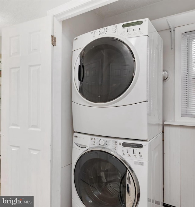 laundry area featuring a textured ceiling and stacked washer and clothes dryer