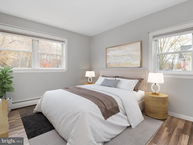 bedroom with hardwood / wood-style floors and a baseboard radiator