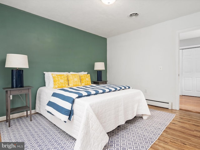 bedroom featuring hardwood / wood-style floors and a baseboard heating unit