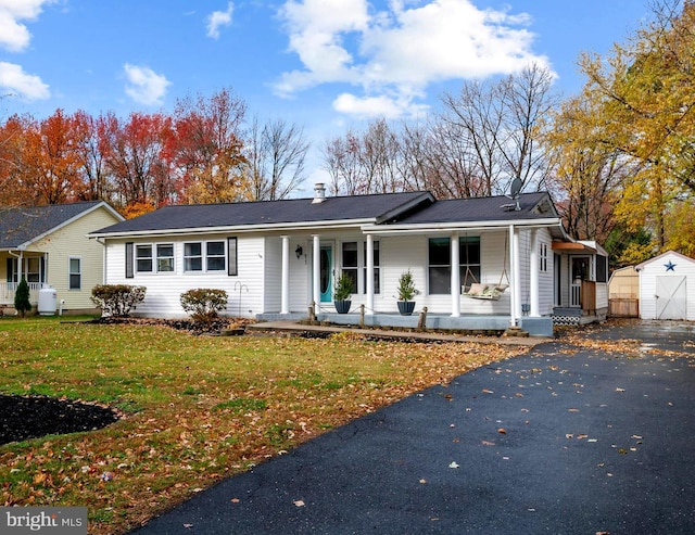 single story home featuring covered porch, a storage shed, and a front lawn