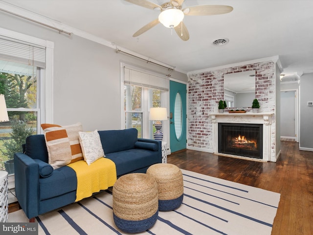 living room featuring crown molding, dark hardwood / wood-style flooring, ceiling fan, and a brick fireplace