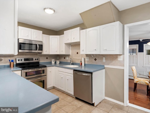 kitchen with white cabinets, sink, light tile patterned floors, appliances with stainless steel finishes, and tasteful backsplash