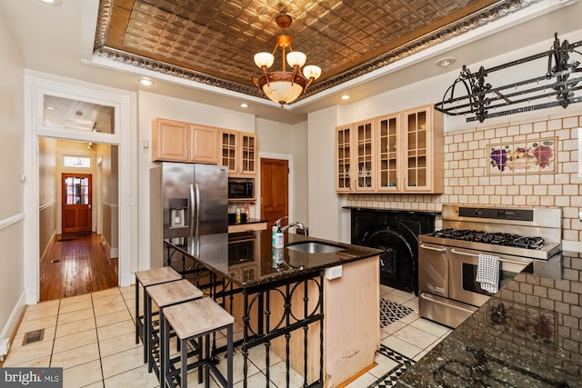 kitchen with sink, hanging light fixtures, stainless steel appliances, light hardwood / wood-style flooring, and an inviting chandelier