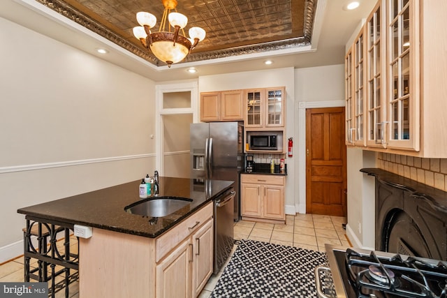 kitchen with light brown cabinets, appliances with stainless steel finishes, an inviting chandelier, a kitchen breakfast bar, and sink