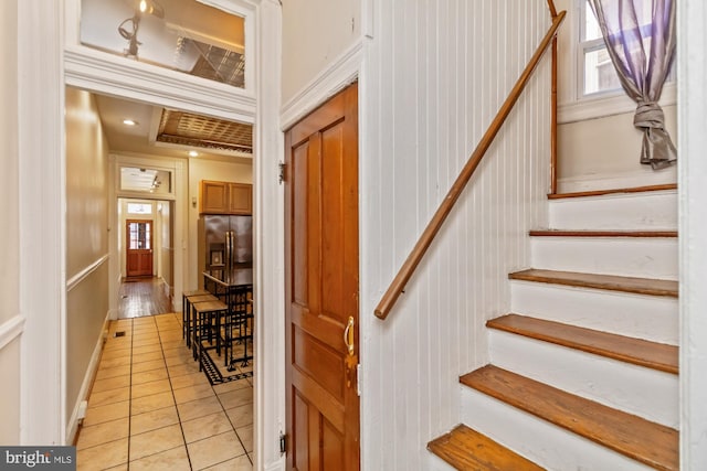 staircase featuring wood walls, ornamental molding, and tile patterned floors