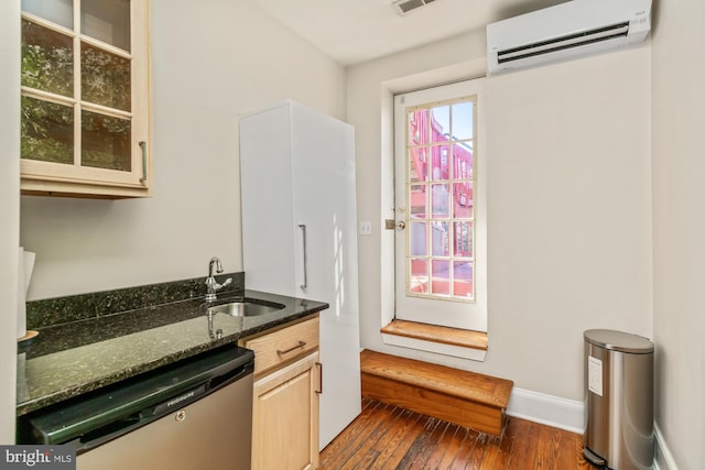 kitchen featuring dark hardwood / wood-style flooring, stainless steel dishwasher, dark stone counters, an AC wall unit, and sink