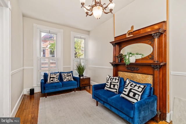 living area with vaulted ceiling, wood-type flooring, and an inviting chandelier