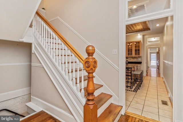 stairs featuring ornamental molding and hardwood / wood-style flooring