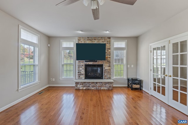 unfurnished living room with french doors, a fireplace, wood finished floors, and visible vents