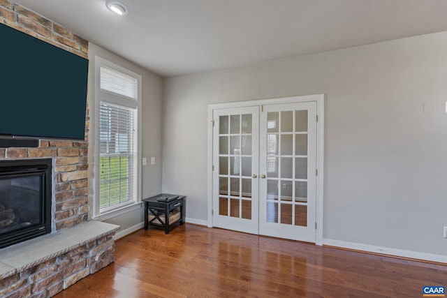 interior space featuring french doors, a fireplace, wood finished floors, and baseboards