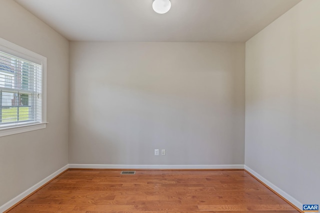 unfurnished room featuring light wood-type flooring, visible vents, and baseboards