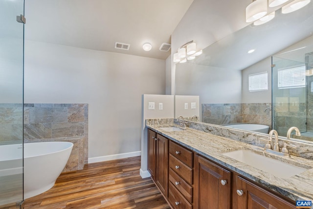 bathroom with double vanity, a freestanding tub, a sink, and visible vents