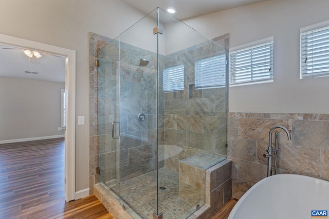 bathroom with tile walls, a soaking tub, visible vents, a shower stall, and wood finished floors