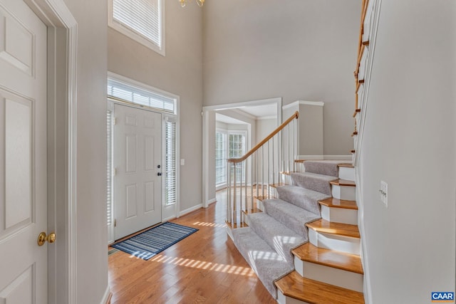 entrance foyer with a high ceiling, stairway, light wood-type flooring, and baseboards