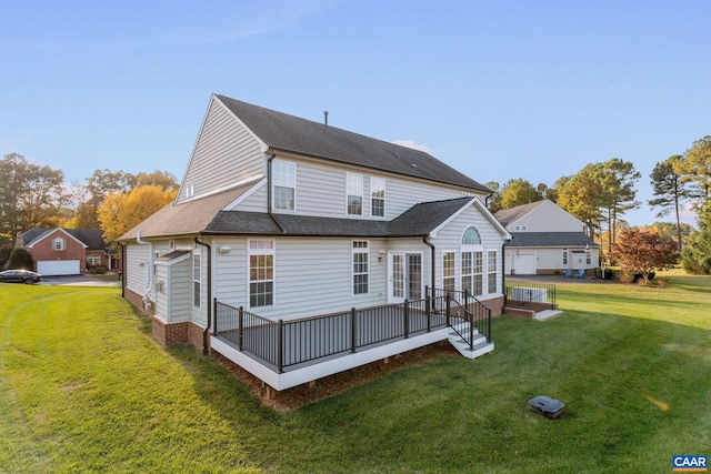 back of house featuring roof with shingles, a lawn, and a deck