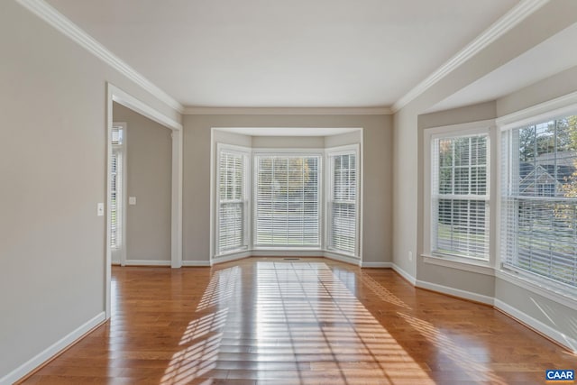 spare room featuring baseboards, wood finished floors, and ornamental molding