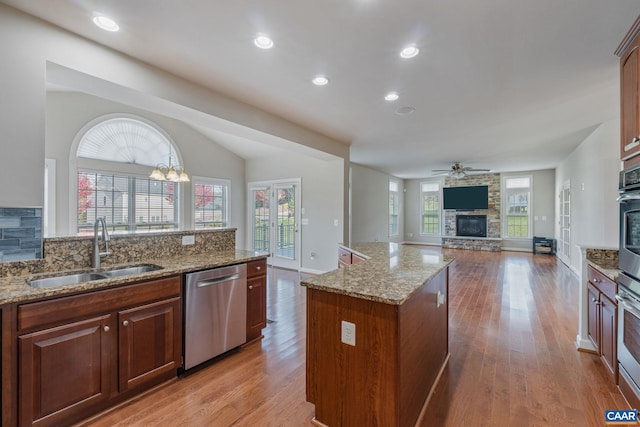 kitchen featuring stainless steel appliances, wood finished floors, a fireplace, and a sink